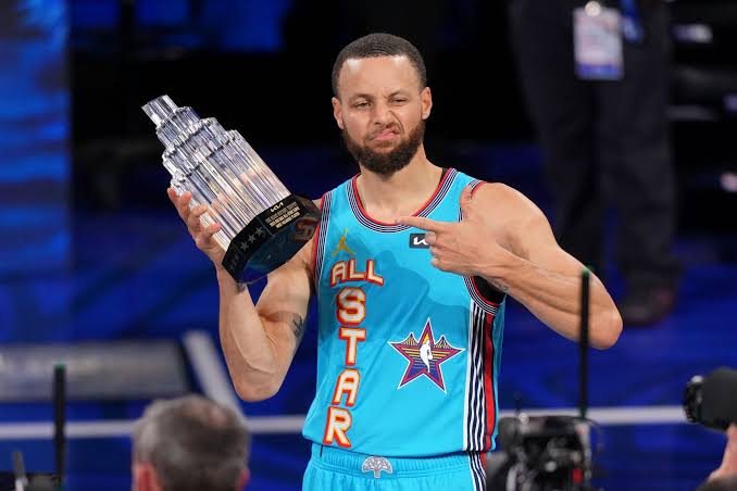 Curry in an All-Star jersey holding the All-Star MVP trophy
