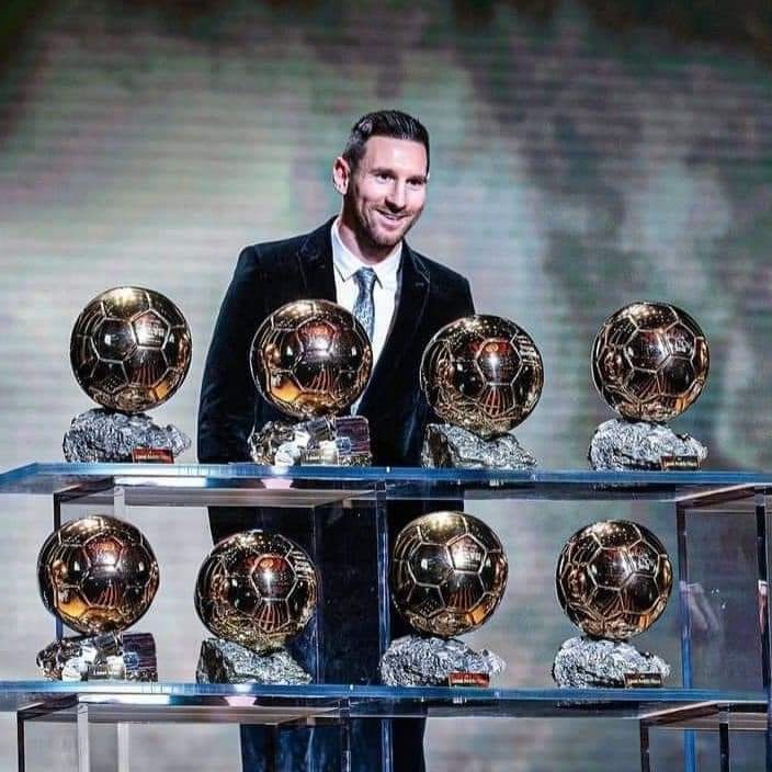 Messi standing behind his eight Ballon d'Or trophies