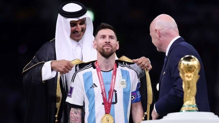 Messi in the black bisht with his medal next to the World Cup trophy